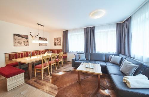 a living room with a blue couch and a table at Appartements Der Fuchsbau in Saalbach Hinterglemm