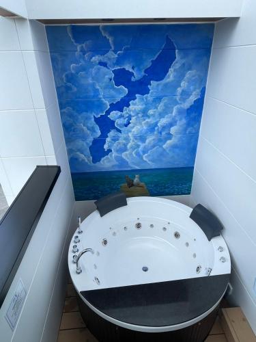 a bathroom with a bath tub with a painting of the ocean at MIRATIO Saphir in Onna