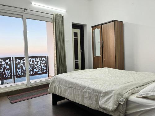 a bedroom with a bed and a large window at Valley View in Kodaikānāl