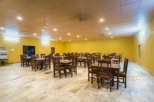 a restaurant with wooden tables and chairs and yellow walls at Marina Luxery resort Jaisalmer in Jaisalmer