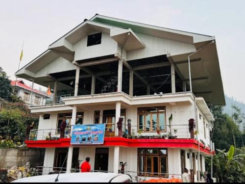 a large white building with a sign in front of it at Wanderlust Homestay By StayApart in Kalimpong