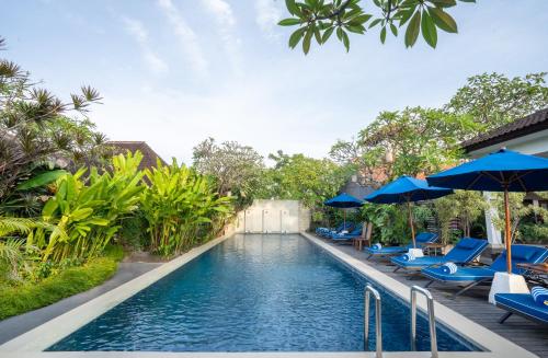 a pool at a resort with blue chairs and umbrellas at Rama Residence Petitenget in Seminyak