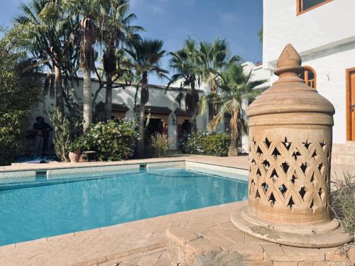 a swimming pool with a fountain next to a house at Riad TAWALA Surfing Mind in Tamraght Ouzdar