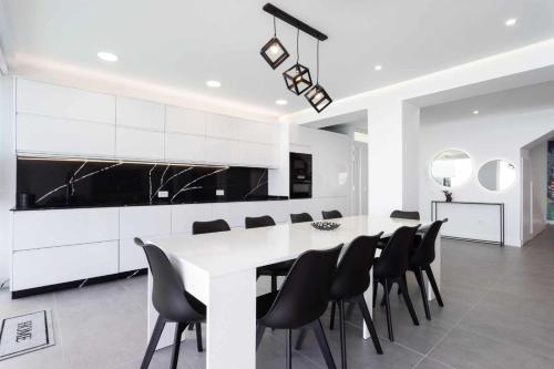 a white kitchen with a table and black chairs at Vivienda vacacional de lujo en el sauzal in Sauzal