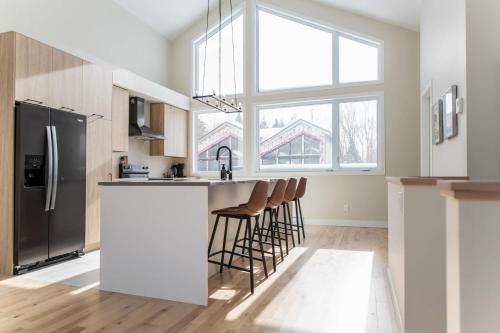 a kitchen with a refrigerator and a counter with stools at Ski Mont Saint-Anne - Absolute Comfort - Mont Lumina in Beaupré