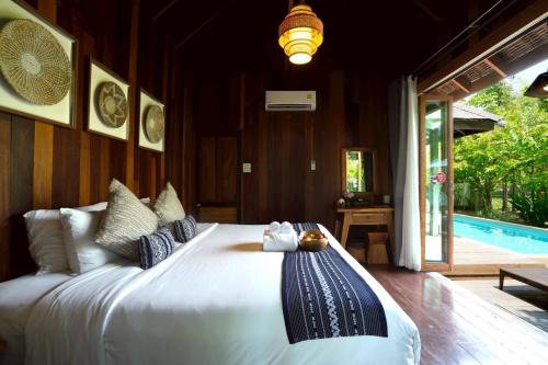 a bedroom with a large white bed and a pool at Tongna Cottage Natural Resort in Chiang Mai
