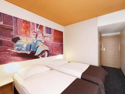 a room with a bed and a painting of a scooter at B&B Hotel Berlin Genshagen-Süd in Ludwigsfelde