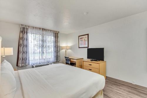 a hotel room with a bed and a television at Clarion Inn Salt Lake City Airport in Salt Lake City
