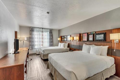 a hotel room with two beds and a television at Clarion Inn Salt Lake City Airport in Salt Lake City