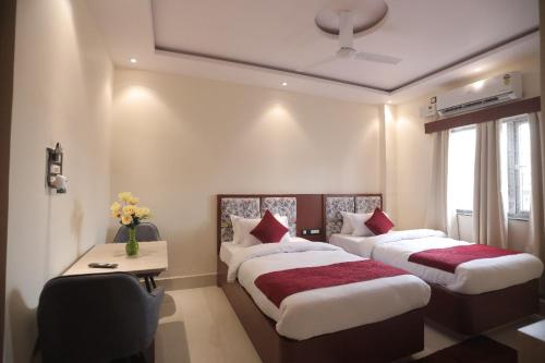 a bedroom with two beds and a table and a window at Hotel Maharani Grand Patna in Patna