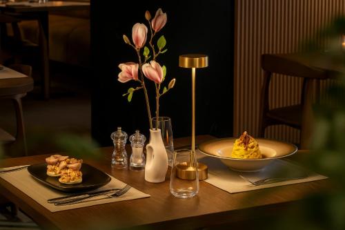a table with a plate of food and a vase of flowers at ONE66 - Luxury Aparthotel in Braşov