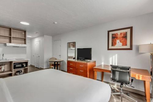 a room with a bed and a desk and a tv at Suburban Studios Salt Lake City Airport in Salt Lake City