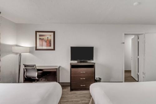 a hotel room with two beds and a flat screen tv at Suburban Studios Salt Lake City Airport in Salt Lake City