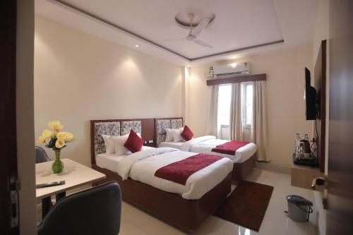 a hotel room with two beds and a desk at Hotel Maharani Grand Patna in Patna