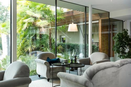 a living room with chairs and a table and windows at Hotel Mignon Meran Park & Spa in Merano