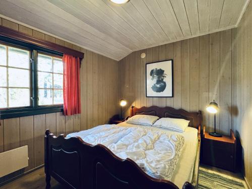 a bedroom with a bed in a room with wooden walls at Briskebu, cosy cabin by ski slopes in Geilo