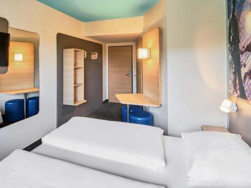 a room with two beds and a table at B&B Hotel Darmstadt in Darmstadt