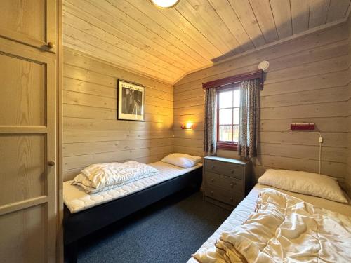 a bedroom with two beds in a wooden cabin at Tvilsombu, cosy cabin close to ski slopes in Geilo