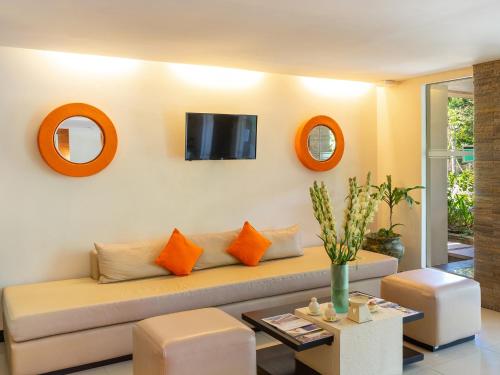 a living room with a couch and a tv on the wall at Discovery Kartika Plaza Hotel in Kuta
