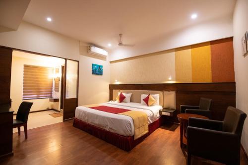 a hotel room with a bed and a desk and chairs at Hotel High Point in Tiruchchirāppalli