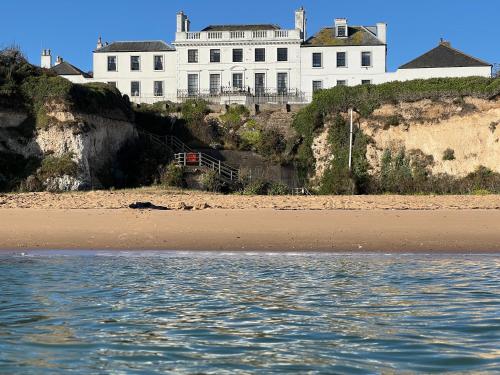 a large white house sitting on top of a beach at Broadstairs Beach Holiday Apartments, opposite Kingsgate Bay with a parking space in Broadstairs