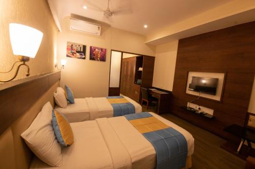 a hotel room with two beds and a television at Hotel High Point in Tiruchchirāppalli