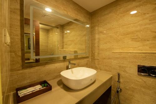 a bathroom with a white sink and a mirror at Hotel High Point in Tiruchchirāppalli