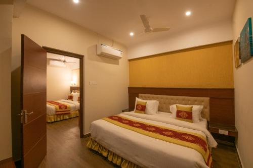 a hotel room with two beds and a mirror at Hotel High Point in Tiruchchirāppalli