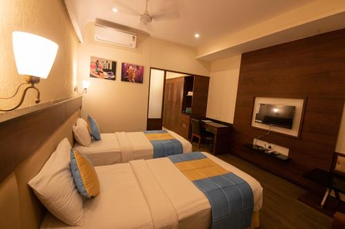 a hotel room with two beds and a television at Hotel High Point in Tiruchchirāppalli