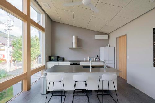 a kitchen with a counter with stools and a sink at Echo Rocks by The Hakuba Collection in Hakuba