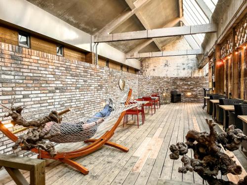 a room with hammocks and tables and a brick wall at Stylish Suite Near Gouden Ham Wifi Ac in Oss
