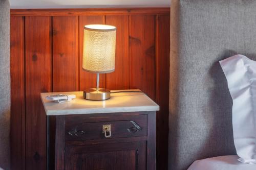 a lamp on a night stand next to a bed at Refúgio do Sol - Azorean Butler in Mosteiros