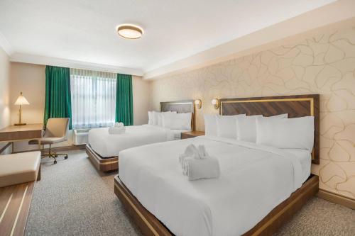 a hotel room with two beds and a desk at Velora Hinton, an Ascend Collection Hotel in Hinton