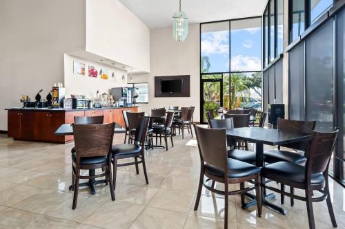a dining room with tables and chairs and a bar at Quality Inn & Suites at Tropicana Field in St. Petersburg