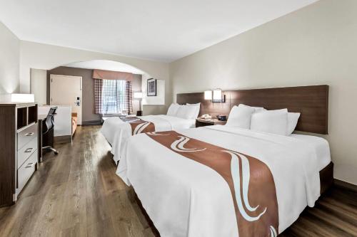 a hotel room with two beds and a bathroom at Quality Inn & Suites near Robins Air Force Base in Warner Robins