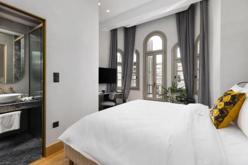 a bedroom with a large white bed and a bathroom at IL CONFORMISTA Casa Storica in Thessaloniki