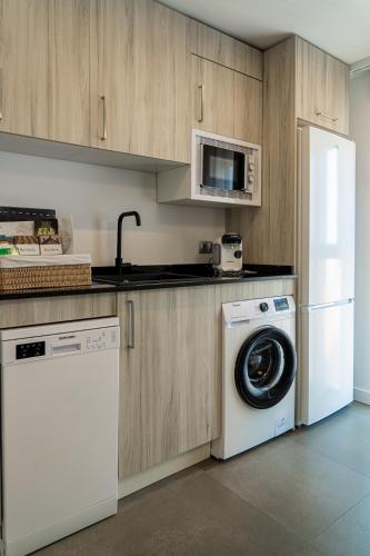a kitchen with a washing machine and a microwave at Piso-loft AOVE pleno centro in Jaén