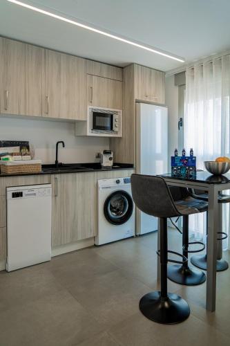 a kitchen with a washer and a table with a chair at Piso-loft AOVE pleno centro in Jaén