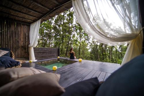 a woman sitting on a deck with a pool in a tent at Villa Experience - Relais Il Termine Elba in Rio Marina