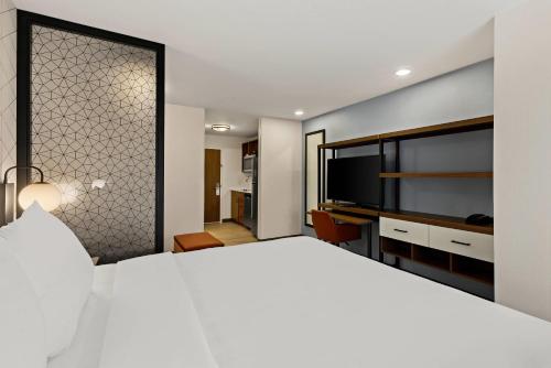a bedroom with a large white bed and a flat screen tv at Everhome Suites Somerset - South Brunswick in Somerset
