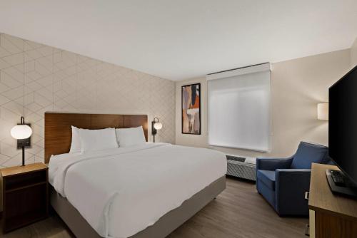 a bedroom with a large white bed and a blue chair at Everhome Suites Somerset - South Brunswick in Somerset