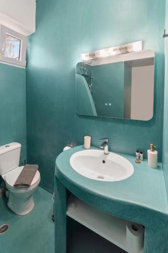 a bathroom with a sink and a toilet and a mirror at Chora Sea Nest, 2-BDR Flat in Andros Town in Andros