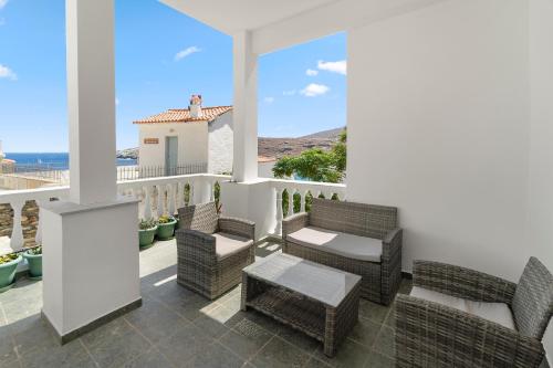 a patio with chairs and a table and a view of the ocean at Chora Sea Nest, 2-BDR Flat in Andros Town in Andros