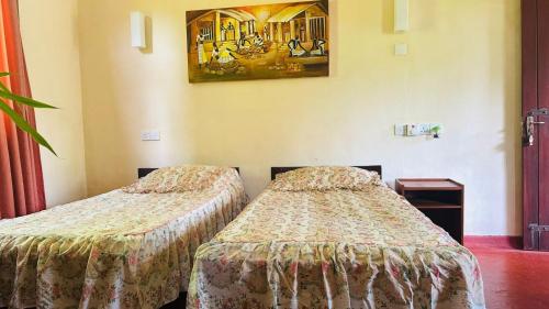 - 2 lits dans une chambre d'hôtel avec une photo sur le mur dans l'établissement Forest Glen, à Kandy