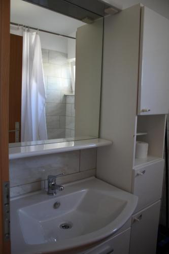 a bathroom with a white sink and a mirror at Apartman Kristina, studio i soba in Primošten