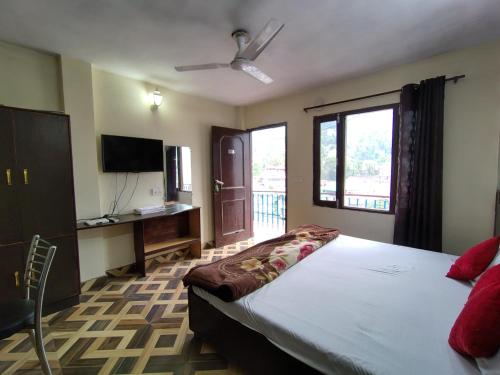 a bedroom with a large bed and a television at Hotel Sandhyana Inn in Dharamshala