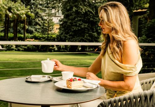 a woman sitting at a table with a piece of cake at Hotel Mignon Meran Park & Spa in Merano