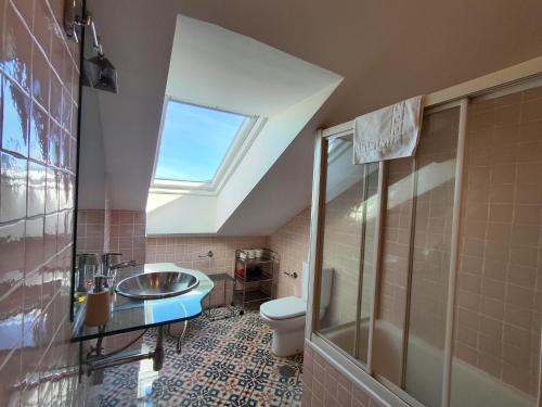 a bathroom with a toilet and a sink and a skylight at Apartamentos Mazuga Rural in Po