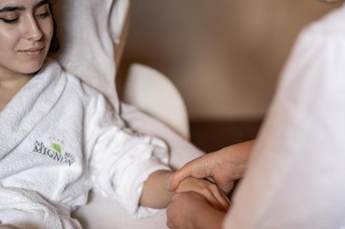 a woman sitting in a hospital bed holding a mans hand at Hotel Mignon Meran Park & Spa in Merano