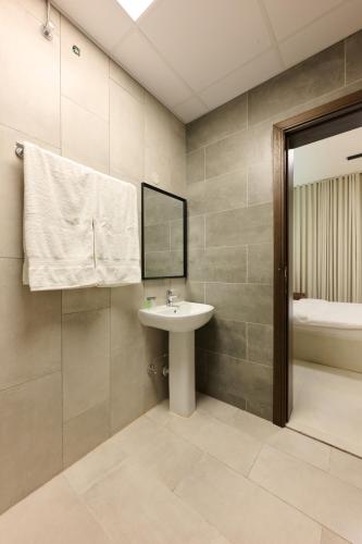 Un baño con lavabo, espejo y bañera. en The Living, en Khor Fakkan